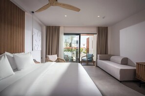 A hotel room with a large bed, a sofa, a chair, and a balcony with a view. - Noble Hotel Suites (Hersonissos)