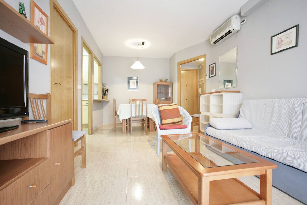 Un salon spacieux comprenant un canapé, une table basse, un téléviseur et un coin repas avec des chaises et une table.