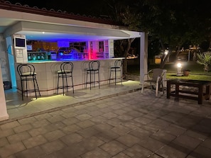 Relax with a drink at this outdoor bar, featuring a sleek bar counter and comfortable seating.