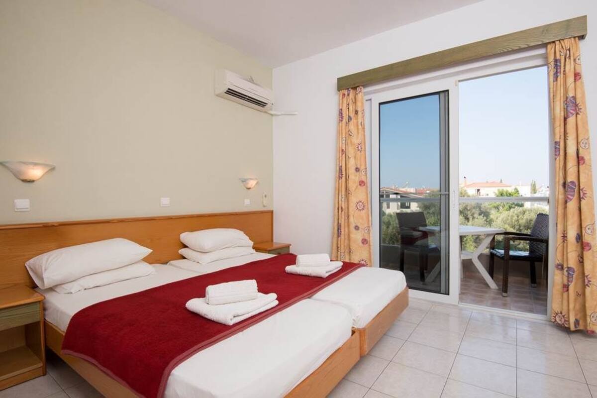 Ein Hotelzimmer mit einem großen Bett, einem Balkon mit Tisch und Stühlen sowie Blick auf die Stadt.