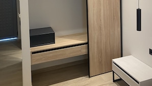 Ein modernes, kleines Zimmer mit einem Etagenbett, einem Holzschrank und einem kleinen Schreibtisch.
