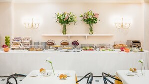 A buffet setup with various food items and floral centerpieces. - Raeli Hotel Luce (Rome)