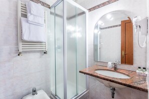 A bathroom with a glass-enclosed shower, a sink with a granite countertop, a towel rack, a mirror, and a telephone. - Raeli Hotel Luce (Rome)