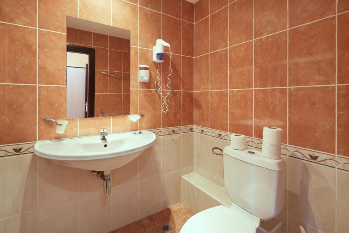 Ein Badezimmer mit Waschbecken, Spiegel, Toilette und Handtuchspender.