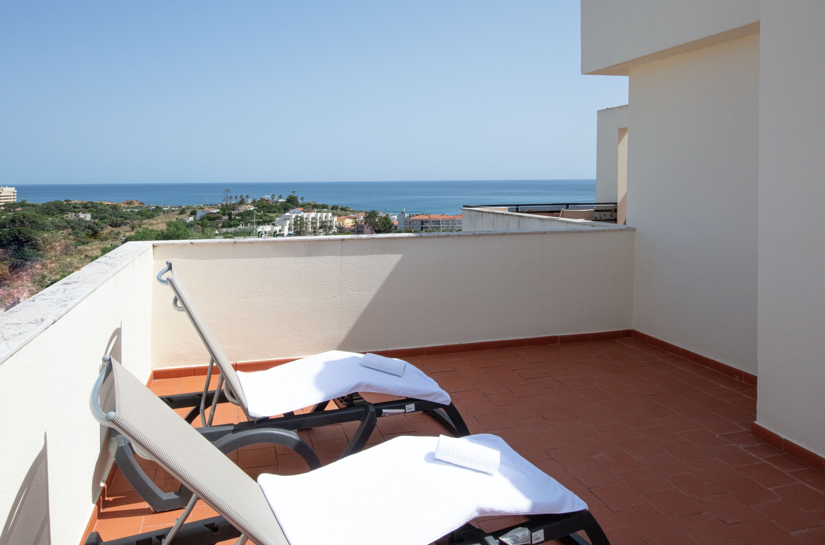 Eine Dachterrasse mit zwei Liegestühlen, Blick aufs Meer und einem gefliesten Boden.