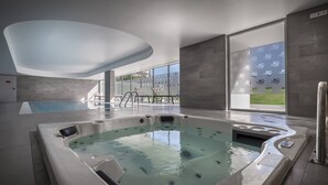 A modern indoor swimming pool with a hot tub, clear glass walls, and a view of the outdoors. - Interpass VAU Hotel & Apartaments (Portimão)