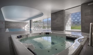 Alberca techada, alberca al aire libre y sombrillas en la alberca