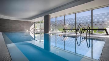 Una piscina cubierta, una piscina al aire libre, sombrillas, tumbonas