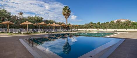 Alberca techada, alberca al aire libre y sombrillas en la alberca