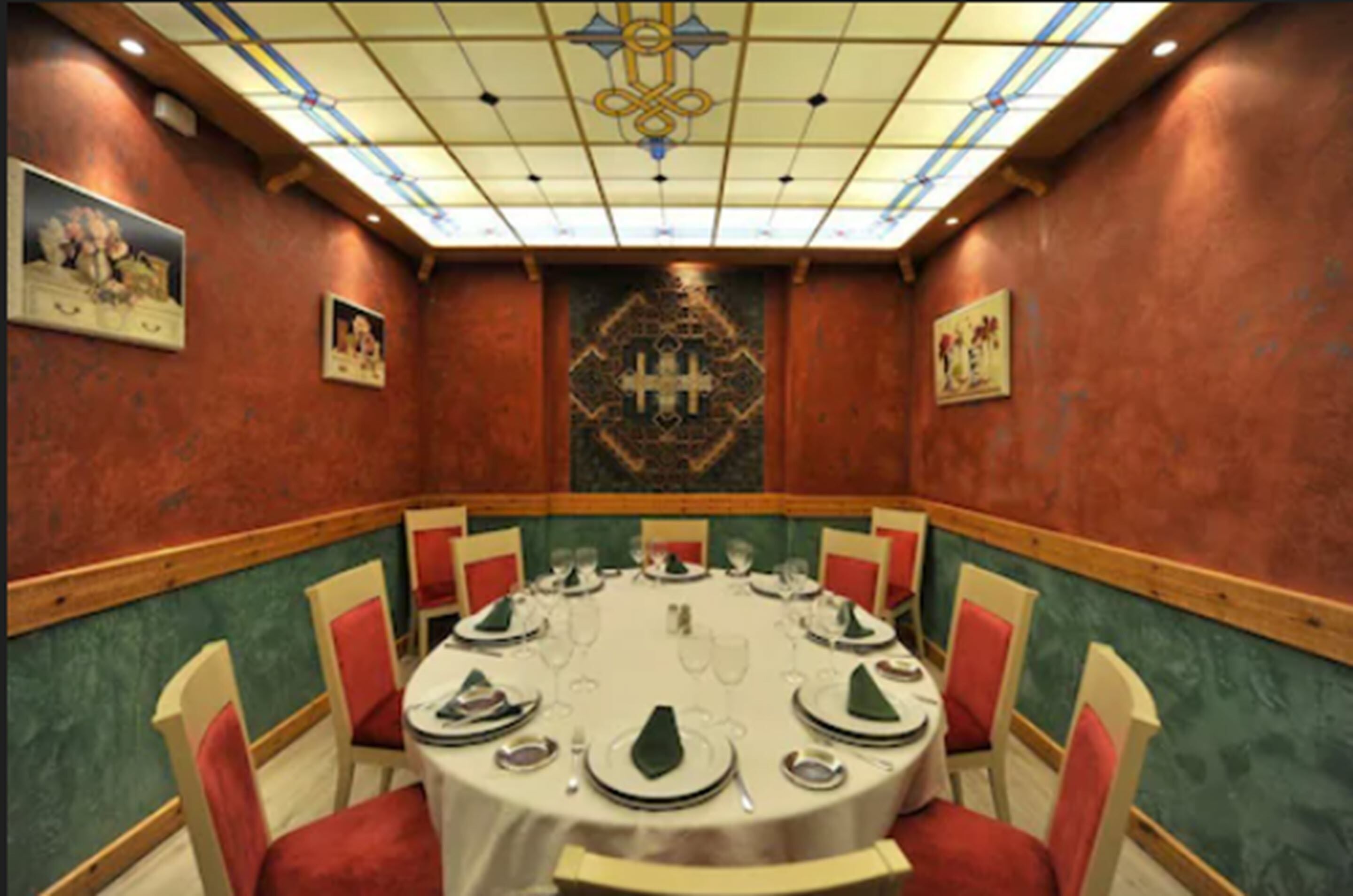 A conference room with a round table, red chairs, and a decorative wall panel.