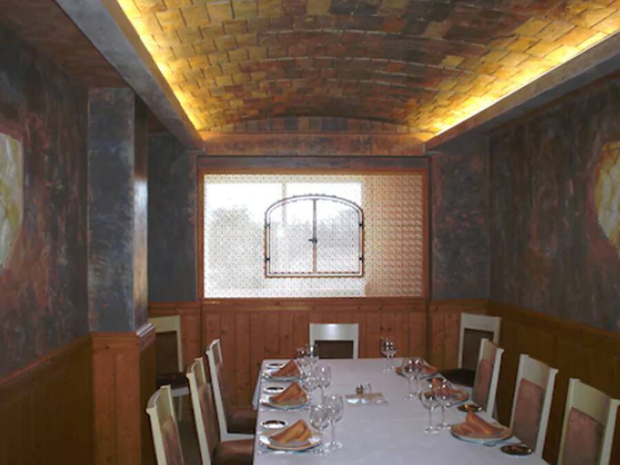 A dining room with a long table set for a meal, wooden paneling on the walls, and a patterned ceiling.