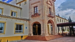 A historic building with a prominent tower, arched windows, and a covered patio area. - Hotel Lozano (Antequera)