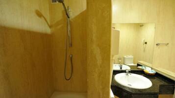 Un baño con ducha, lavamanos y espejo.