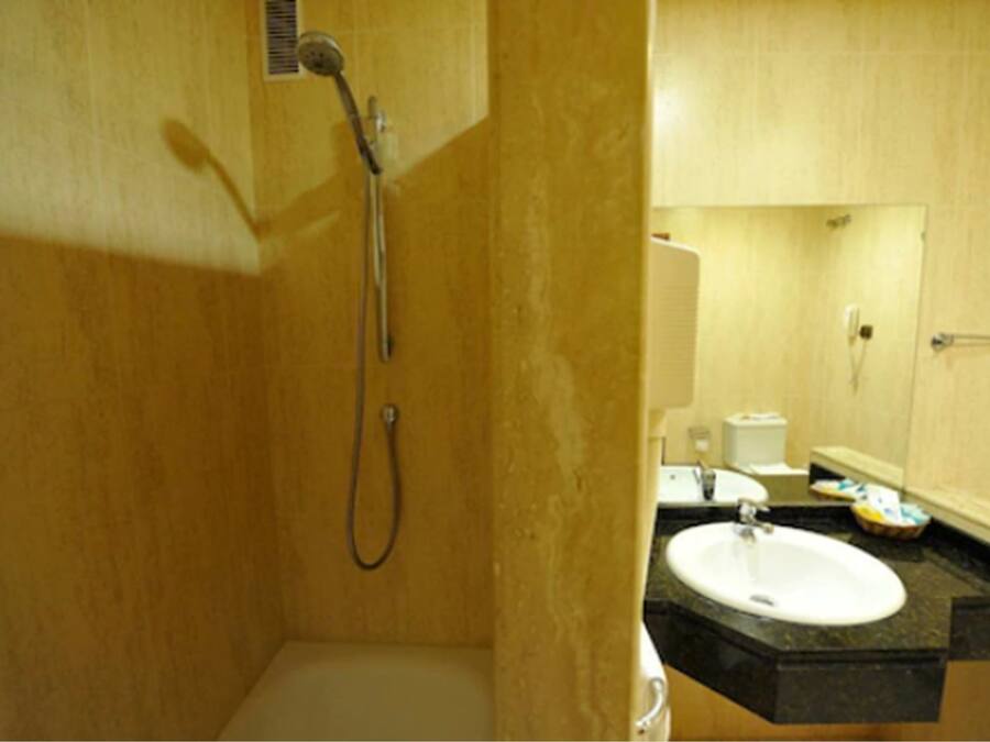 Un baño con ducha, lavamanos y espejo.