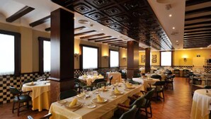 A restaurant with multiple tables set for dining, featuring a checkered floor pattern and a high ceiling with geometric designs. - Hotel Lozano (Antequera)