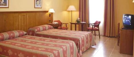 A hotel room with two beds, a television, a desk, and a chair.