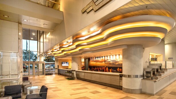 A modern lobby with a curved ceiling, a reception desk, and seating area. - Garden Court Marine Parade (Durban)