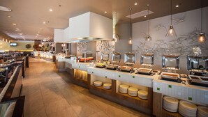 A buffet area with multiple food stations, a counter with plates, and a seating area with tables and chairs. - Garden Court Marine Parade (Durban)