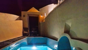 Una piscina con escalones de acceso, rodeada de muros y una puerta al fondo.