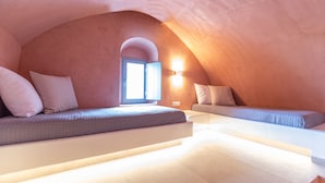 Un dormitorio en el ático con dos camas empotradas, un tragaluz y una lámpara fijada a la pared.