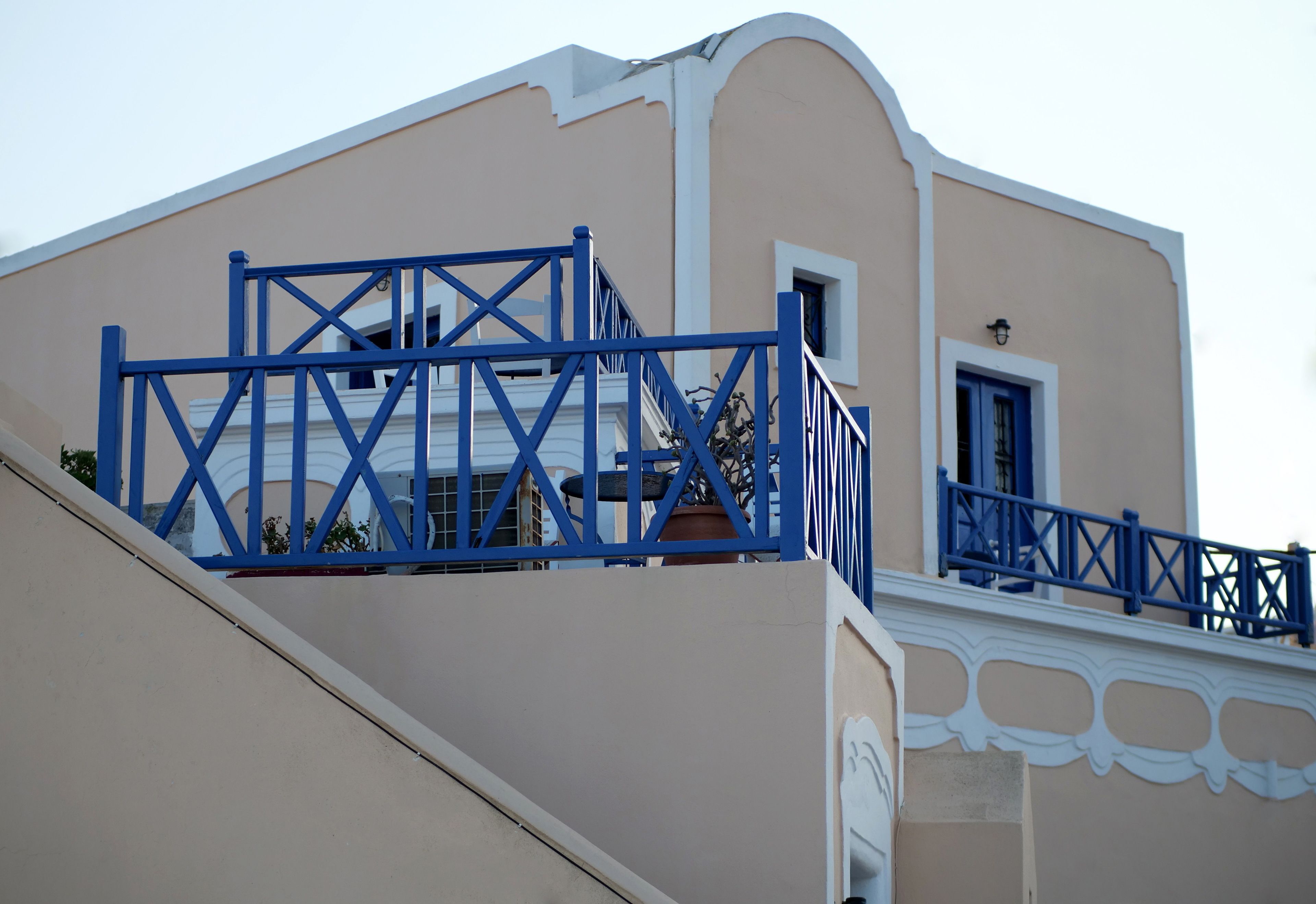 A building with a beige facade, blue railings, and a white decorative trim.