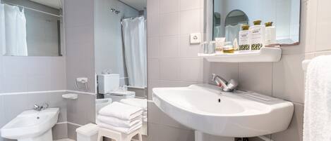 Un baño moderno con un bidé, un lavamanos, un espejo y una ducha.