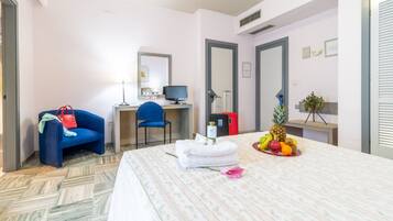 Une chambre d’hôtel équipée d’un lit, d’un bureau, d’une chaise, d’un ordinateur et d’un panier de fruits.