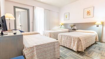 Camera d'albergo con due letti, una scrivania, una sedia, una televisione e uno specchio.