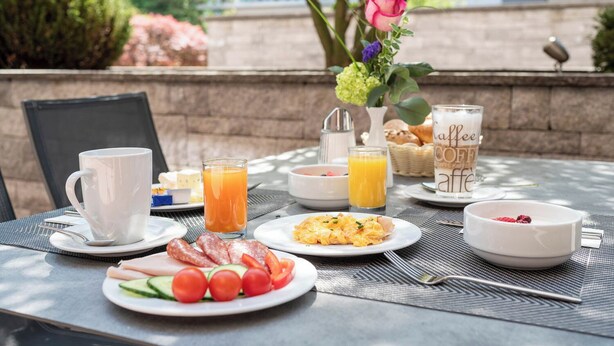 Una mesa de desayuno con platos de comida, una taza de café y un vaso de jugo de naranja.
