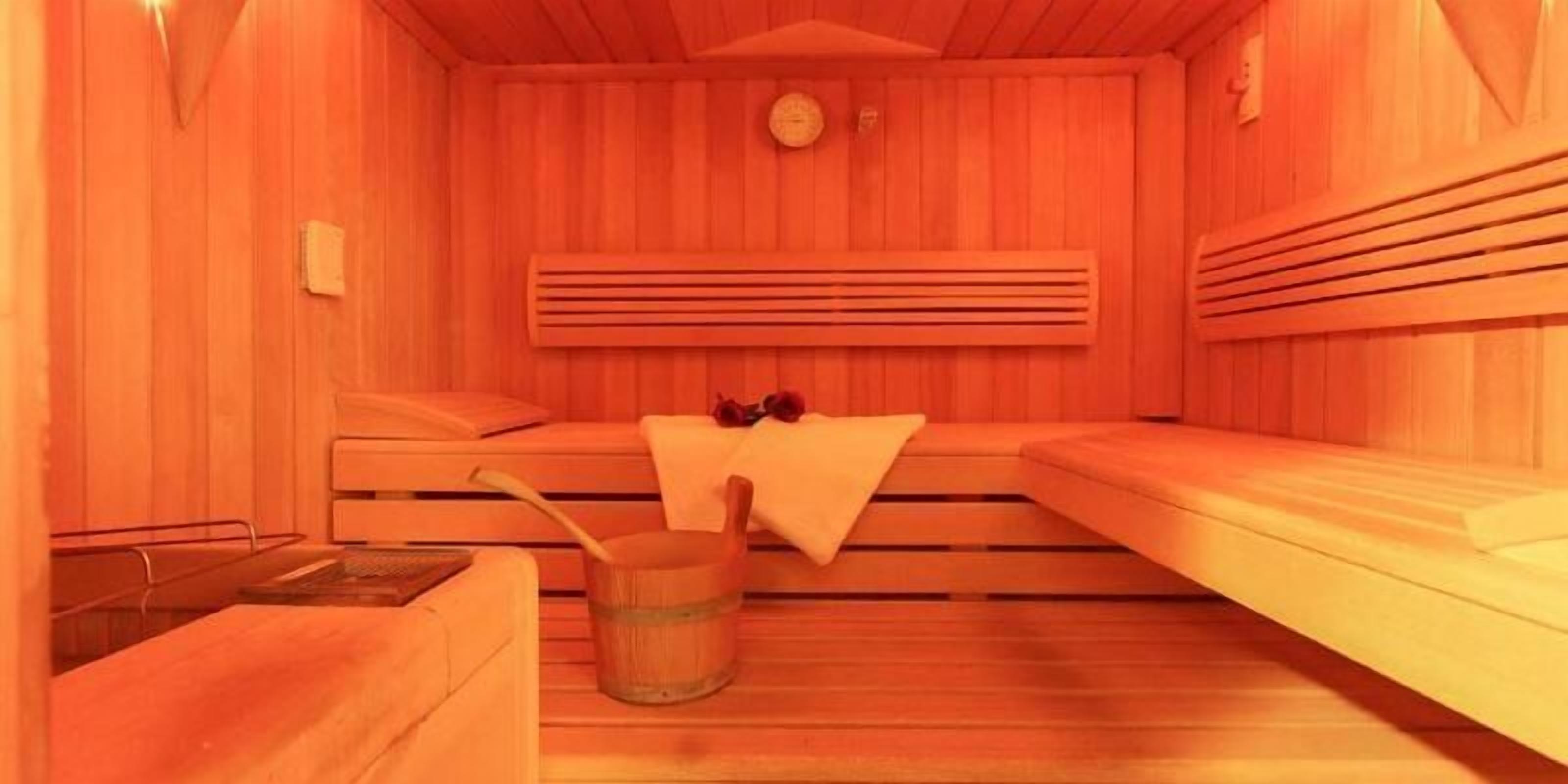 Ein Saunaraum mit Holzbänken, einem Holzfass und einem Handtuch.