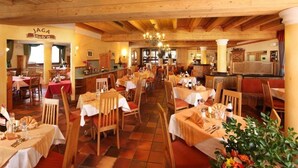 Un restaurante con interiores de madera, varias mesas de comedor y un candelabro.