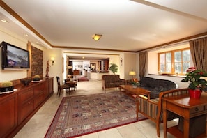 Relax in a spacious living area with a high ceiling, featuring a large rug, mounted TV, and comfortable seating.