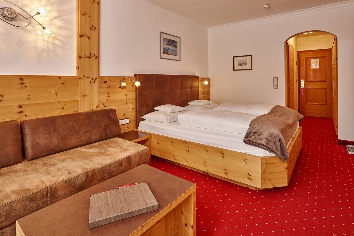 A wooden room with a bed, a sofa, and a desk.