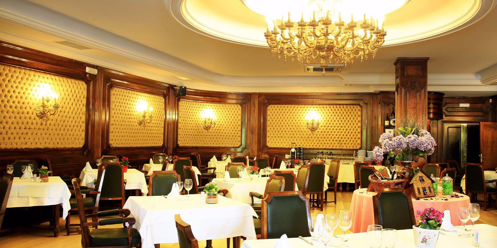 A formal dining room with multiple tables, chairs, and a chandelier.