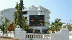 A white building with a signboard in front. - Mobor Beach Resort (GOA)