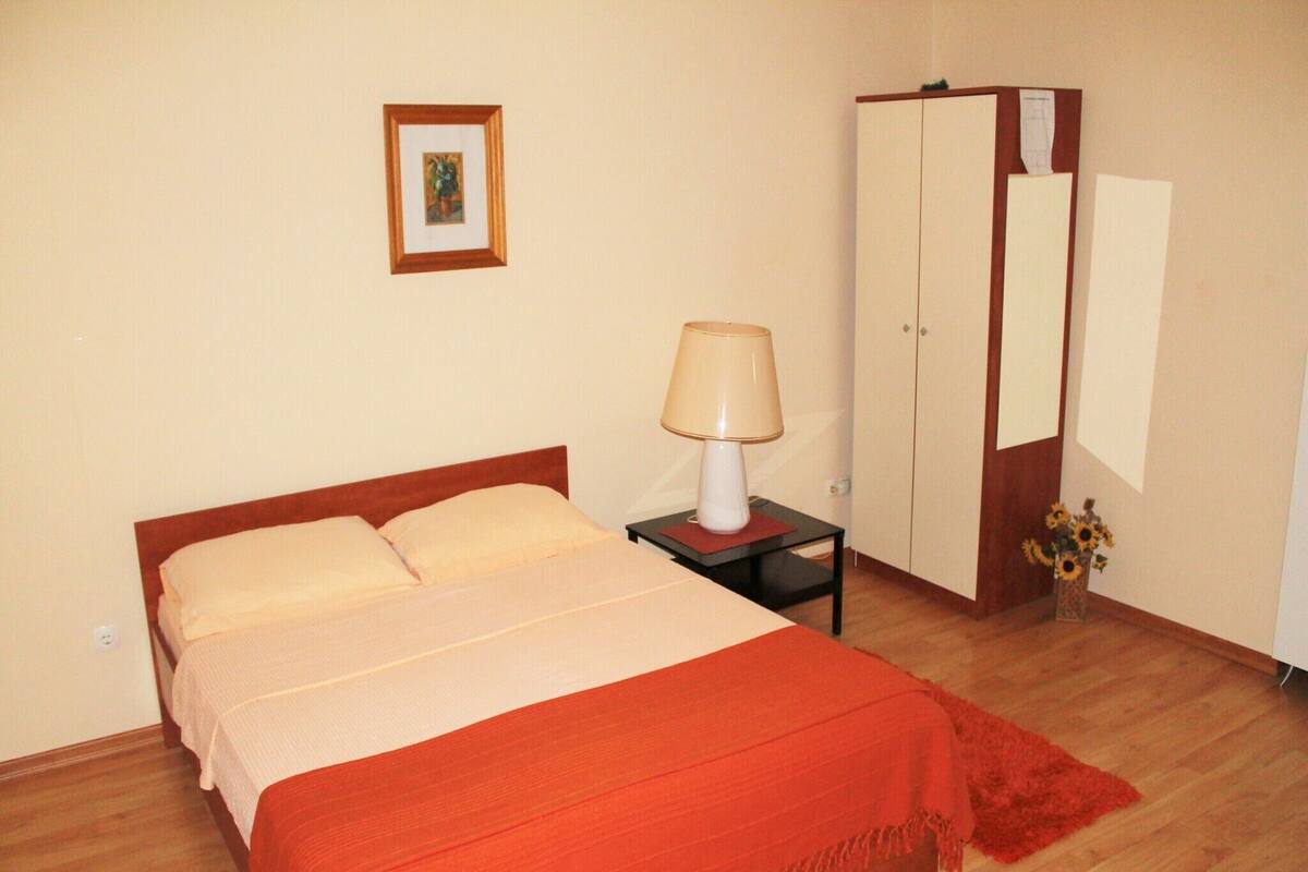 Une chambre à coucher avec un lit, une table de chevet, une lampe, une armoire et un tableau encadré au mur.