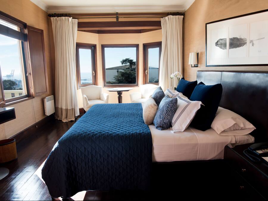 A hotel room with a large bed, a desk, and a view of the city.