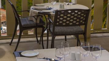 A dining table set for four with a view of a port and cranes in the background.