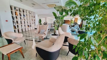 Un vestíbulo moderno con arreglos de asientos, una estantería y plantas de interior.
