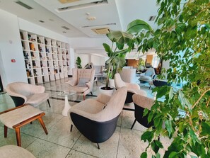 Un vestíbulo moderno con arreglos de asientos, una estantería y plantas de interior.