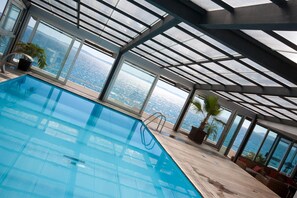 An indoor swimming pool with a view of the ocean through large windows. - Jona Split Rooms (Podstrana)