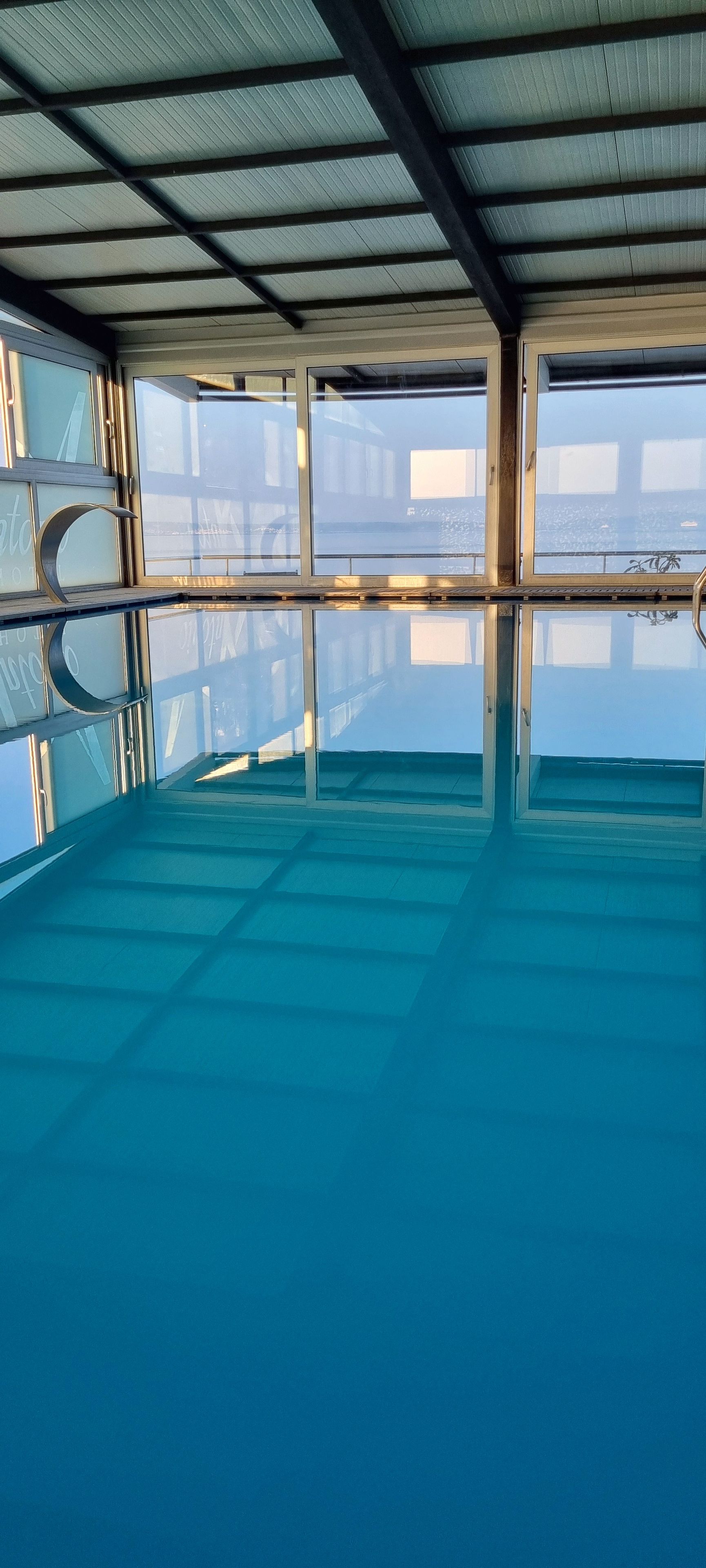 Ein großes Hallenbad mit klaren Glaswänden und einer Metallkonstruktion für das Dach.