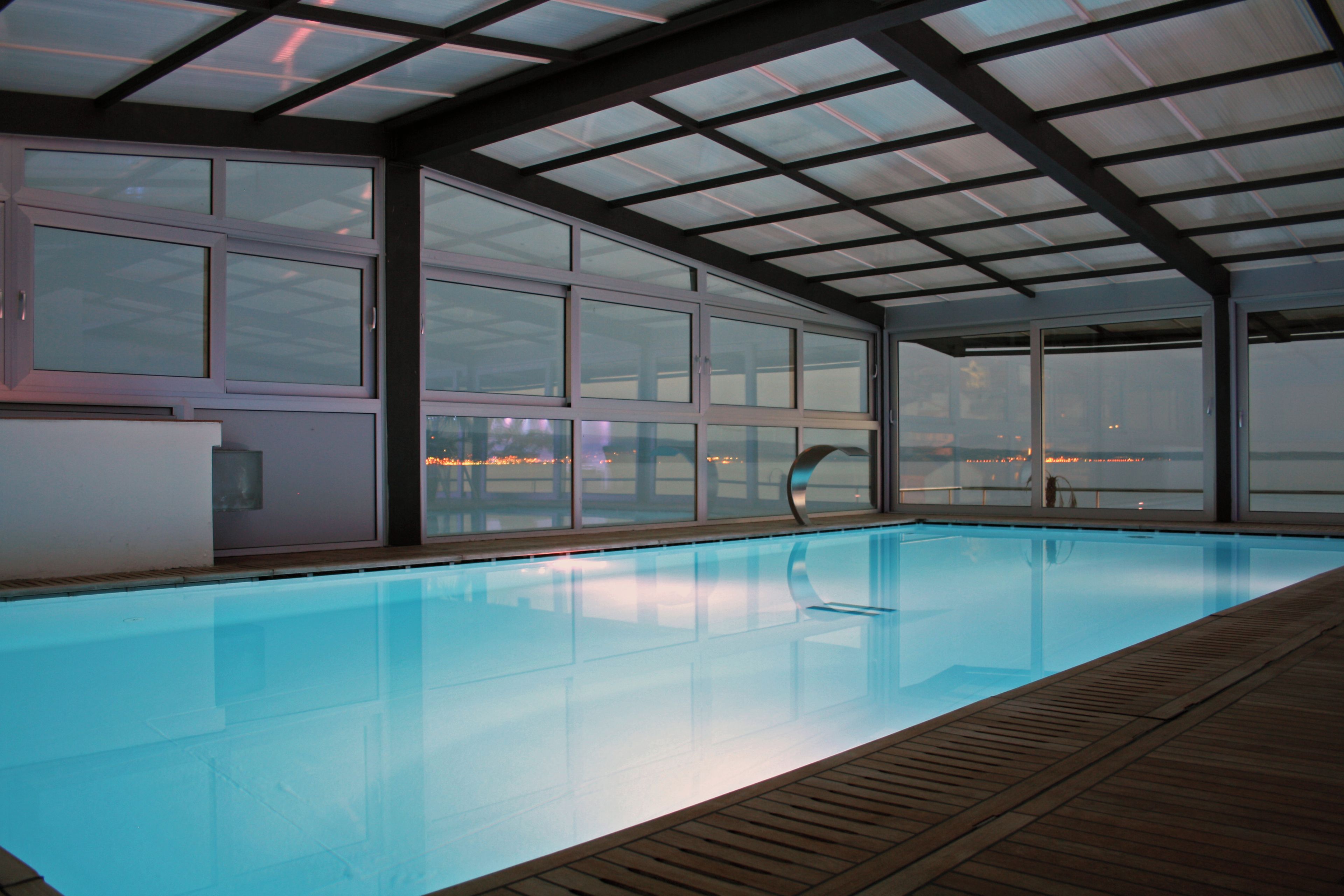 An indoor swimming pool with a view of a cityscape through large windows.