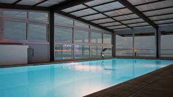 An indoor swimming pool with a view of a cityscape through large windows.