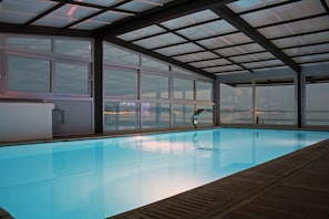 An indoor swimming pool with a view of a cityscape through large windows. - Jona Split Rooms (Podstrana)