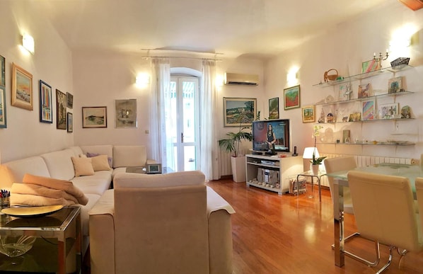 A modern living room with a sofa, TV, and a glass dining table. - Klarina Apartments (Split)