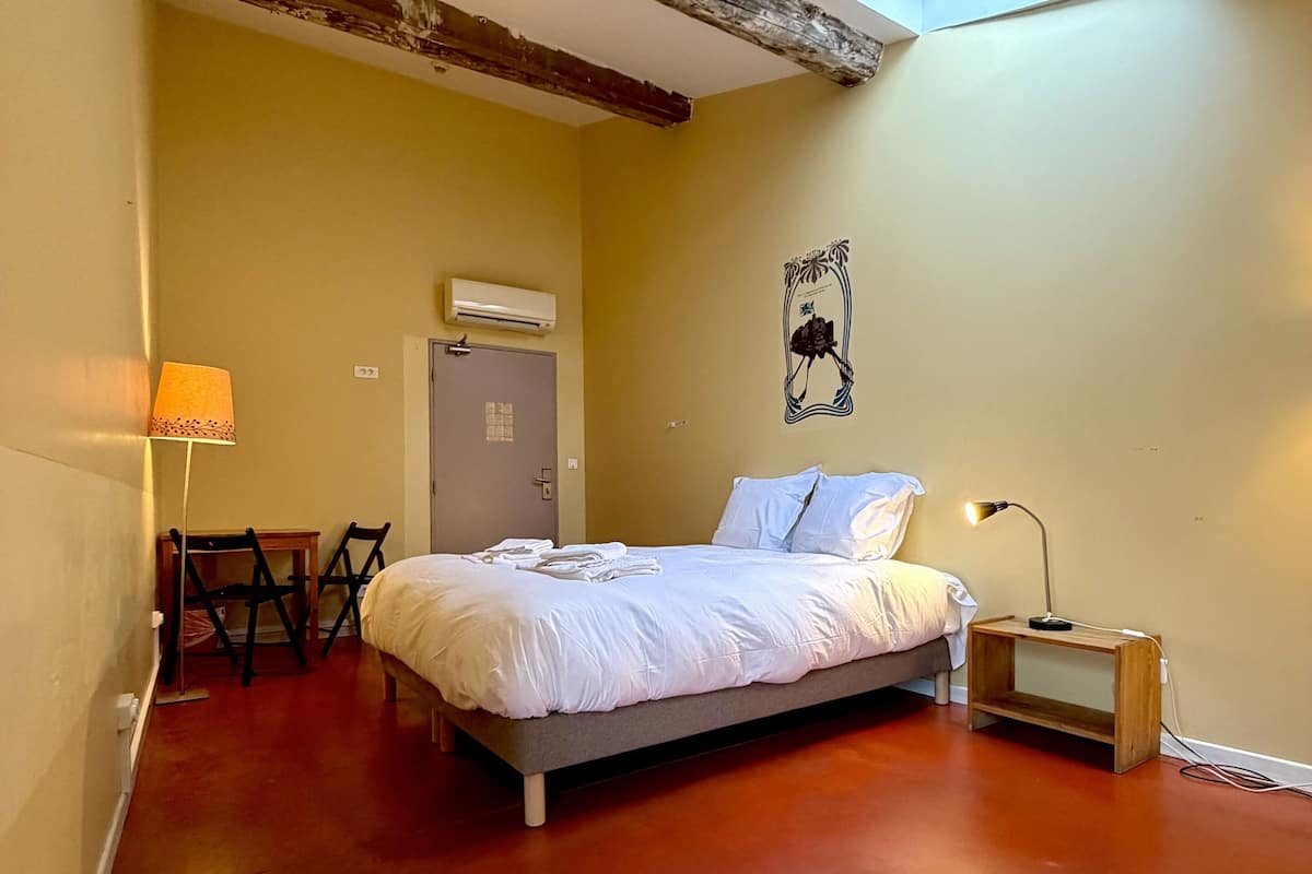 Une chambre à coucher comprenant un lit, un bureau, une chaise, un climatiseur et une lucarne.