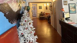 Un espacio interior festivo con un árbol de Navidad blanco, una escalera y un balcón con luces de colores.