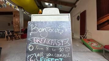 Un letrero en una pizarra anuncia desayuno de 8 a 10 de la mañana, incluye un bufé.
