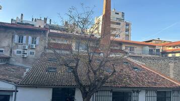 A building with a tiled roof, a chimney, and a tree in front.